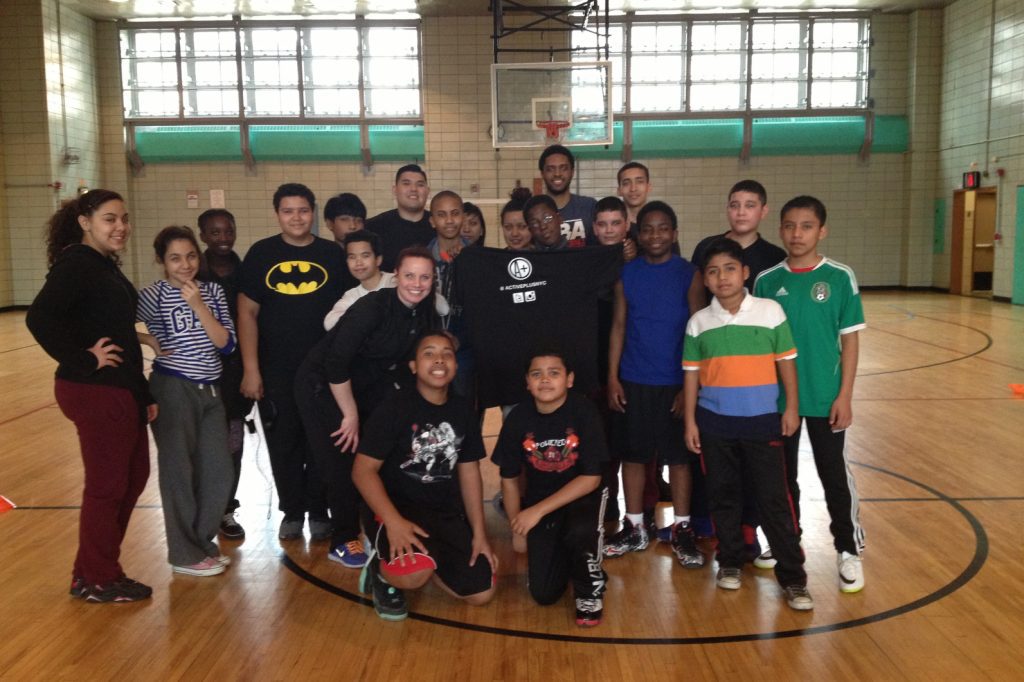Tarik Kitson '08 with school-aged children posing by a basketball hoop