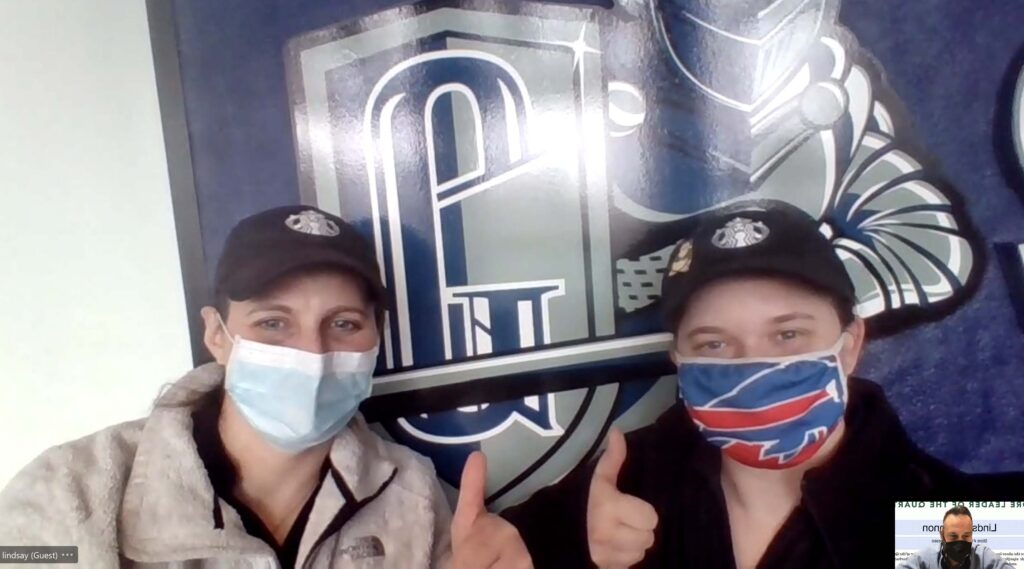 Manager Lindsay Cannon (left) standing in front of Geneseo shield with Brittany Taylor.