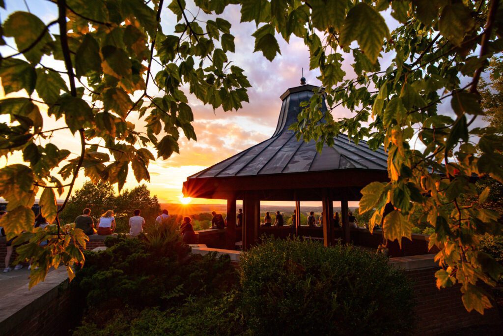 Geneseo students watch an orange sunset from the gazebo.