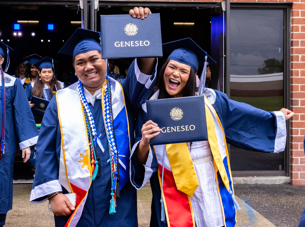 Two graduates show their diplomas after graduation.