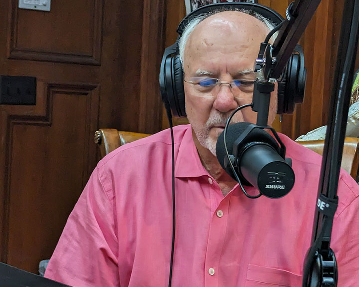 Portrait of George Speedy speaking into a microphone